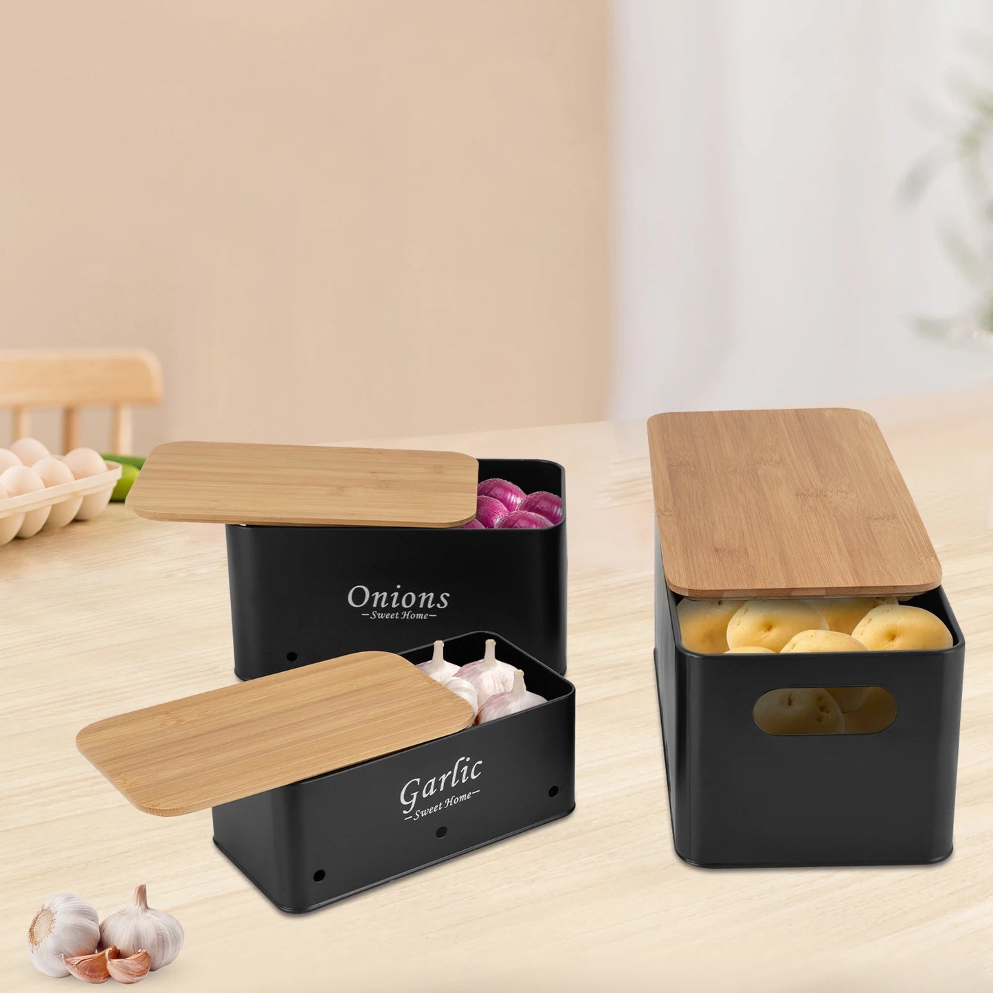 Schwarze Aufbewahrungsboxen für Zwiebeln, Knoblauch und Kartoffeln mit Bambusdeckeln auf Küchenarbeitsplatte.