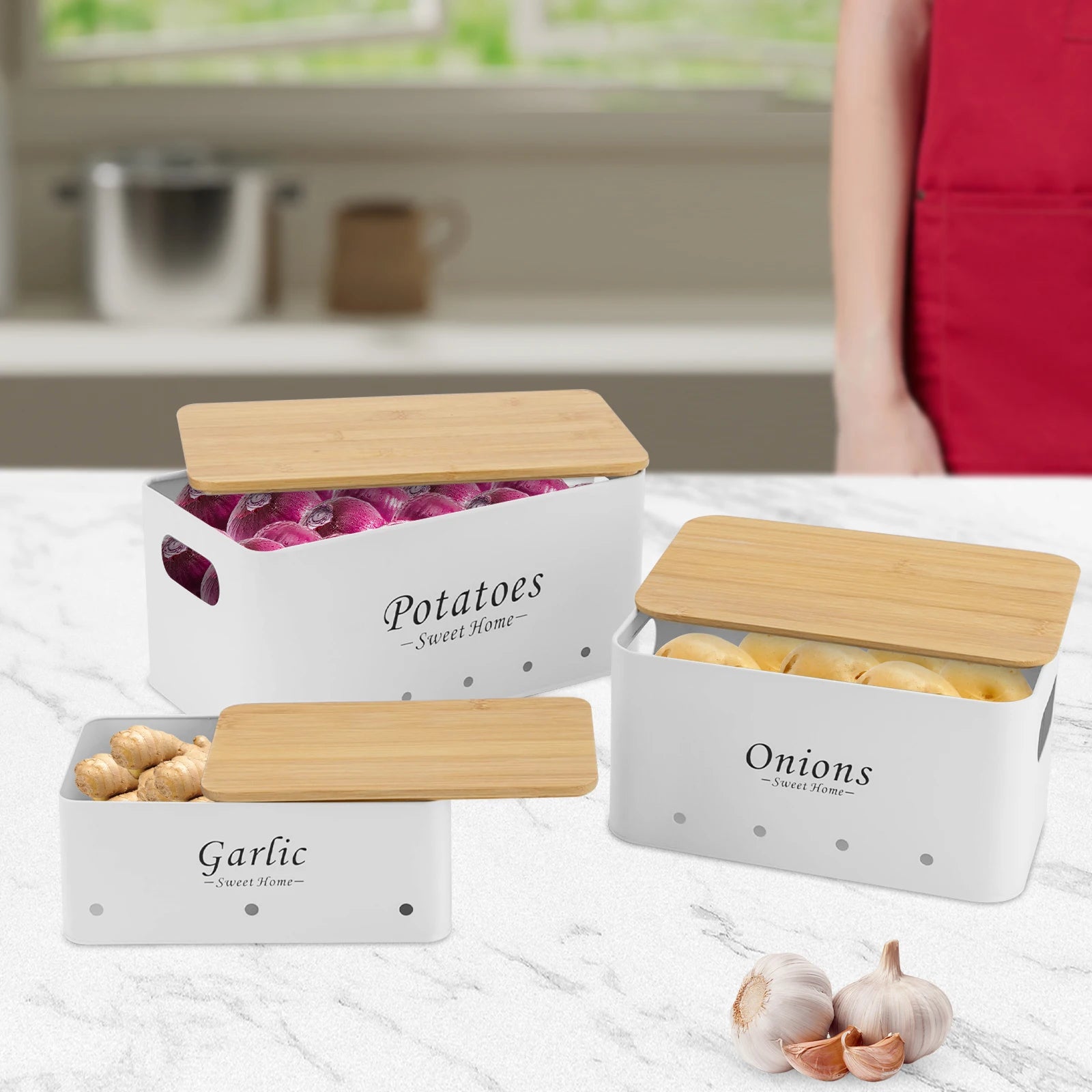 Weiße Aufbewahrungsboxen für Kartoffeln, Zwiebeln und Knoblauch mit Bambusdeckeln auf Marmoroberfläche.