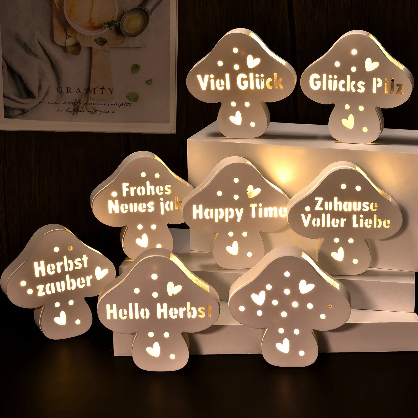 Mehrere beleuchtete Pilzfiguren aus Gips mit verschiedenen Schriftzügen wie Viel Glück, Zuhause Voller Liebe, Happy Time und Hello Herbst