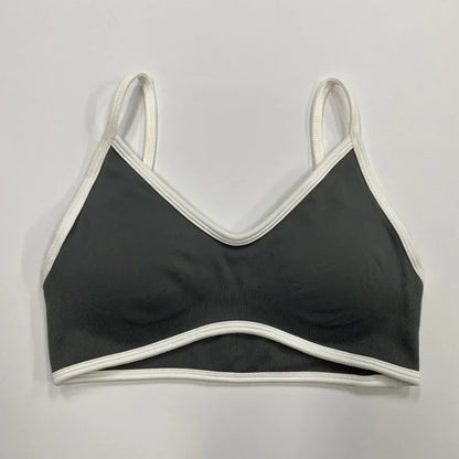 Dunkelgrauer nahtloser Damen Sport-BH mit weißen Abschlüssen und schmalen Trägern auf neutralem Hintergrund.