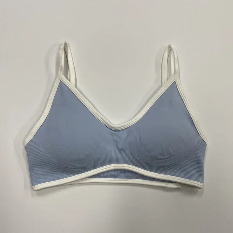 Hellblauer nahtloser Damen Sport-BH mit weißen Abschlüssen und schmalen Trägern auf neutralem Hintergrund.