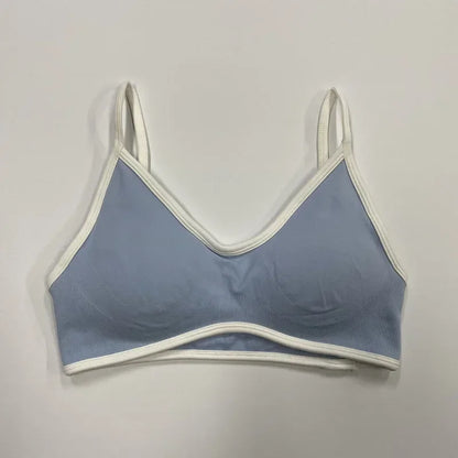 Hellblauer nahtloser Damen Sport-BH mit weißen Abschlüssen und schmalen Trägern auf neutralem Hintergrund.