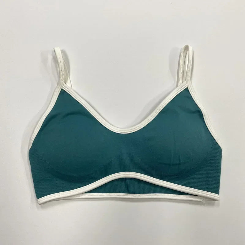 Petrolfarbener nahtloser Damen Sport-BH mit weißen Abschlüssen und schmalen Trägern auf neutralem Hintergrund.