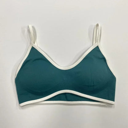 Petrolfarbener nahtloser Damen Sport-BH mit weißen Abschlüssen und schmalen Trägern auf neutralem Hintergrund.