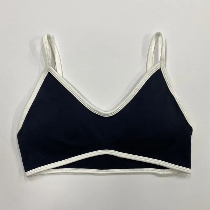 Schwarzer nahtloser Damen Sport-BH mit weißen Abschlüssen und schmalen Trägern auf neutralem Hintergrund.