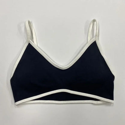 Schwarzer nahtloser Damen Sport-BH mit weißen Abschlüssen und schmalen Trägern auf neutralem Hintergrund.