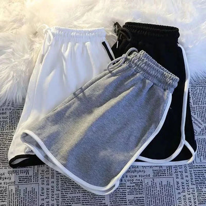 Übereinanderliegende Damen Sport Shorts in Grau, Weiß und Schwarz mit seitlicher Paspelierung.