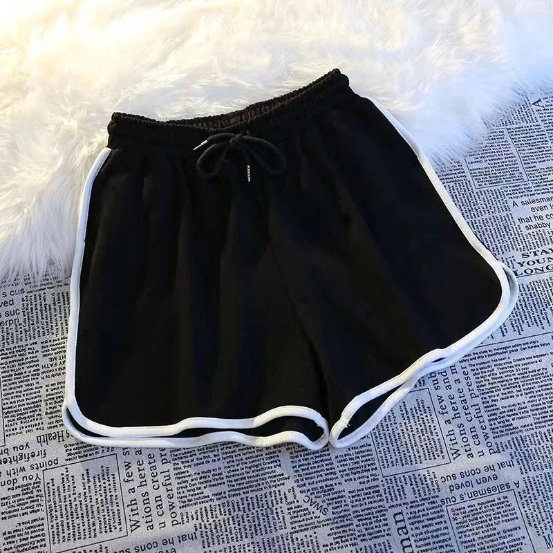 Schwarze Damen Sport Shorts mit weißer Paspelierung und elastischem Bund auf Textiluntergrund.